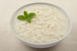 Risotto albeisa style al latte, gocce di fondente e frutta secca sabbiata